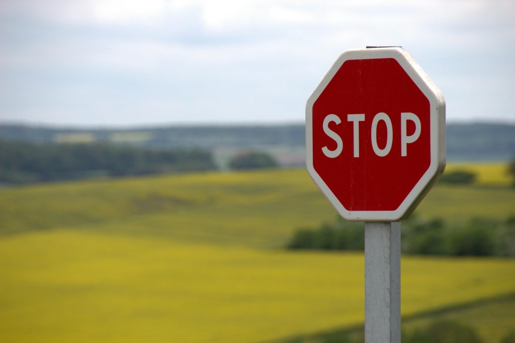 Stop Sign on Road with Fields of grass in background.